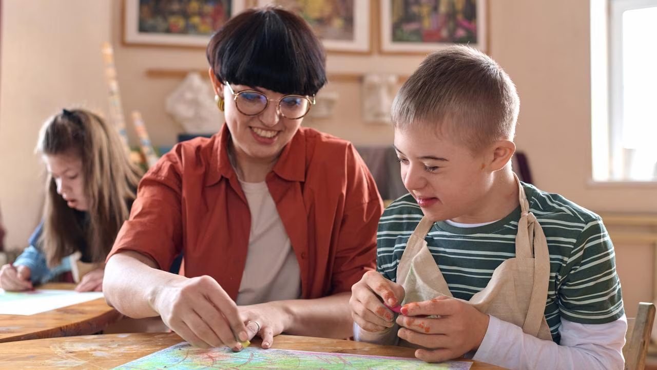 A support worker warmly guiding a participant through a hands-on activity